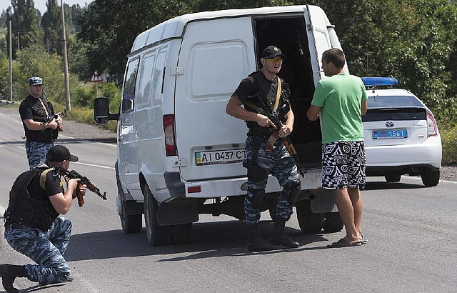 Self-proclamed Donetsk People's Republic policemen search a minivan near Shakhtarsk, Donetsk region, eastern Ukraine on Monday, July 28, 2014. An international police team abandoned its attempt to reach the crash site of a Malaysia Airlines plane for a second day running Monday as clashes raged in a town on the road to the area.(AP Photo/Dmitry Lovetsky)