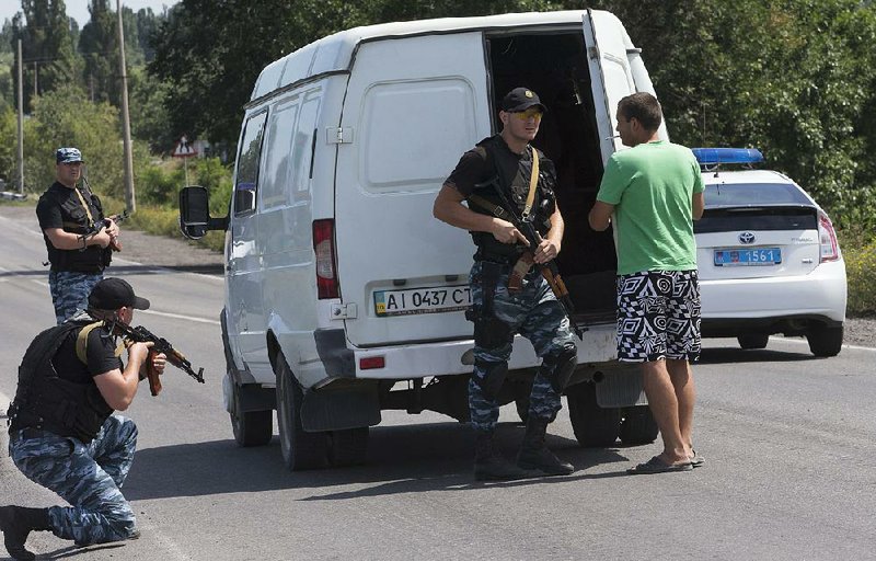 Self-proclamed Donetsk People's Republic policemen search a minivan near Shakhtarsk, Donetsk region, eastern Ukraine on Monday, July 28, 2014. An international police team abandoned its attempt to reach the crash site of a Malaysia Airlines plane for a second day running Monday as clashes raged in a town on the road to the area.(AP Photo/Dmitry Lovetsky)