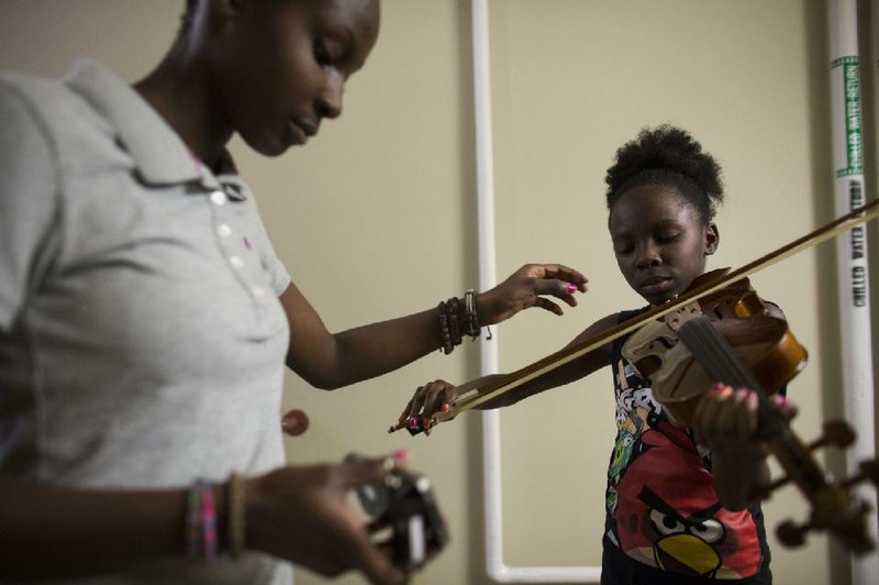 Dajua Hollis, 13, (left) uses an iPhone app to help tune Faith Hollis’ violin in the hallway during the Lorenzo Smith Music Camp at the Mosaic Templars Cultural Center on Thursday. Students in the sixth through 12th grades learned a variety of music-related topics, including how to properly tune instruments, stage presence and music fundamentals.