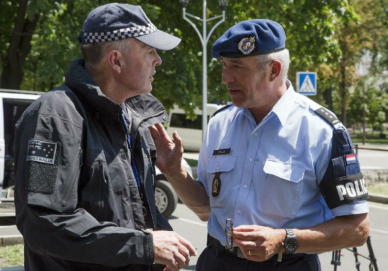 A Dutch police officer (right) talks with an Australian officer in the city of Donetsk, eastern Ukraine, on Sunday. A team of international police officers that had been due to visit the site of the Malaysian plane disaster in eastern Ukraine canceled the trip Sunday after receiving reports of fighting in the area.