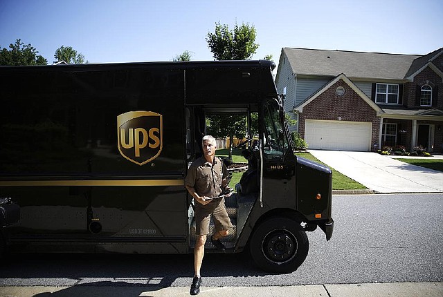 United Parcel Service driver Marty Thompson steps off a truck while making deliveries in Cumming, Ga., in June. UPS on Tuesday reported a second quarter profit of $454 million, or 49 cents a share, down from $1.07 billion, or $1.13 a share, a year ago.