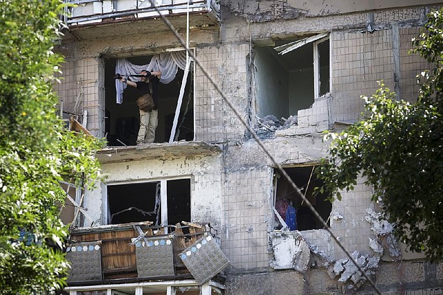 A man takes pictures of a damaged apartment house after an artillery barrage Tuesday in Donetsk in eastern Ukraine. Residents said the shells came from the direction of Ukrainian army positions.