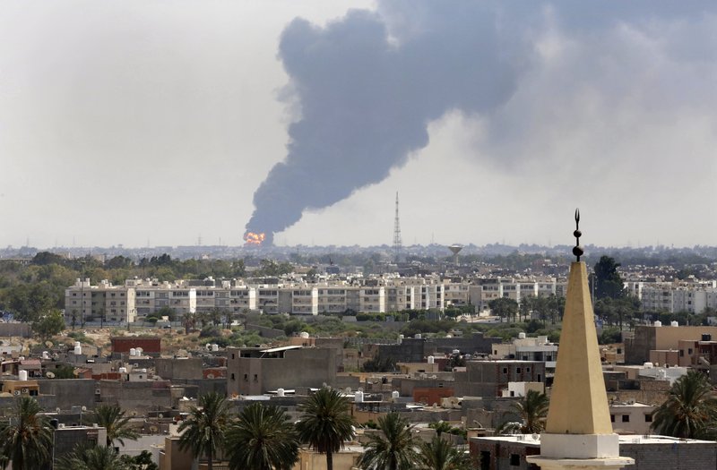 Black smoke billows over the skyline as a fire at the oil depot for the airport rages out of control after being struck in the crossfire of warring militias battling for control of the airfield, in Tripoli, Libya Monday, July 28, 2014. The latest violence to plague the country has so far killed scores of people and wounded hundreds as foreigners flee the chaos. Libya's interim government said in a statement that the fire could trigger a "humanitarian and environmental disaster" in Tripoli, appealing for "international help" to extinguish the inferno.