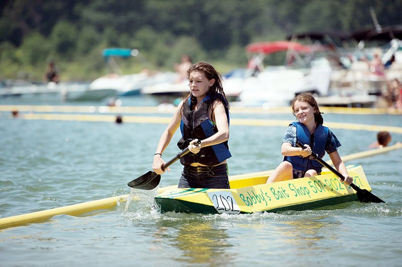 Tori Osborn, front, 14, and her sister, Caitlyn Osborn, 13, paddle to the finish line Saturday to win the team youth division at the 28th annual World Championship Cardboard Boat Races in Heber Springs. The teenagers said they had never seen the cardboard boat races until they were asked to pilot a boat for their summer employer, 
Bobby Cox.