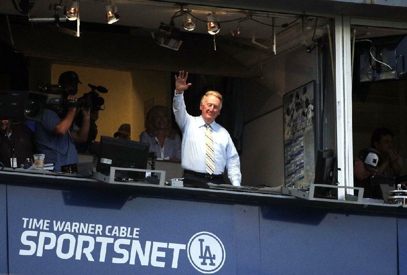 Los Angeles Dodgers broadcaster Vin Scully, shown acknowledging the crowd during a game at Dodger Stadium on Tuesday, will return for a 66th season with the team in 2015.