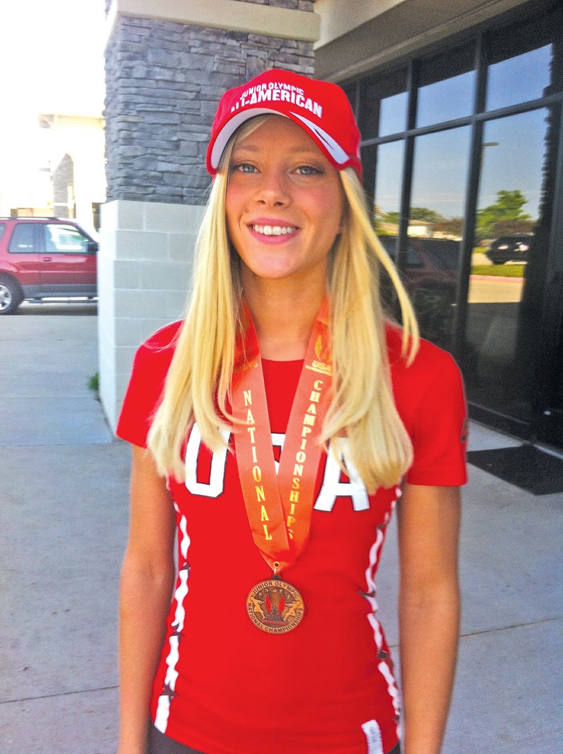 STAFF PHOTO HENRY APPLE Amanda Dillon dons the cap and the medal she received for earning All-American status last weekend during the 2014 USATF National Junior Olympic Track &amp; Field Championships, which concluded last weekend in Houston.