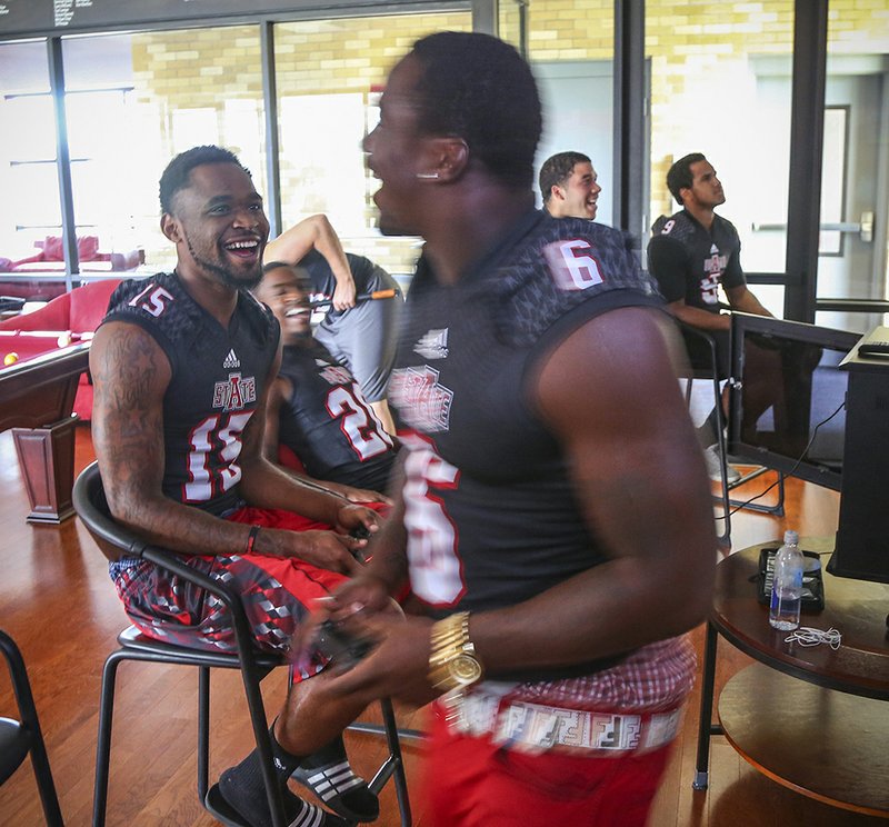 Arkansas Democrat-Gazette/Stephen B. Thornton CAMPUS CHEER: Arkansas State University football players Tres Houston, left, Brandon Cox, center, and Frankie Jackson, right, laugh over their game-console basketball game in a player-recreation room before visiting with the media on campus Wednesday in Jonesboro. The Red Wolves begin fall practice today under first-year coach Blake Anderson, preparing for their Aug. 30 opener against visiting Montana State.