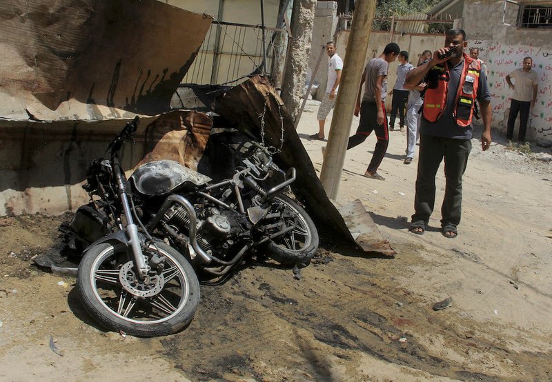 A Palestinian medic inspects the wreckage of a motorcycle caused by an Israeli airstrike in Rafah on Thursday, July 31, 2014. Fadel Elmeghary, an Islamic Jihad member, was killed in the airstrike, while on his motorcycle in Rafah, according to Gaza health official Ashraf al-Kidra. 