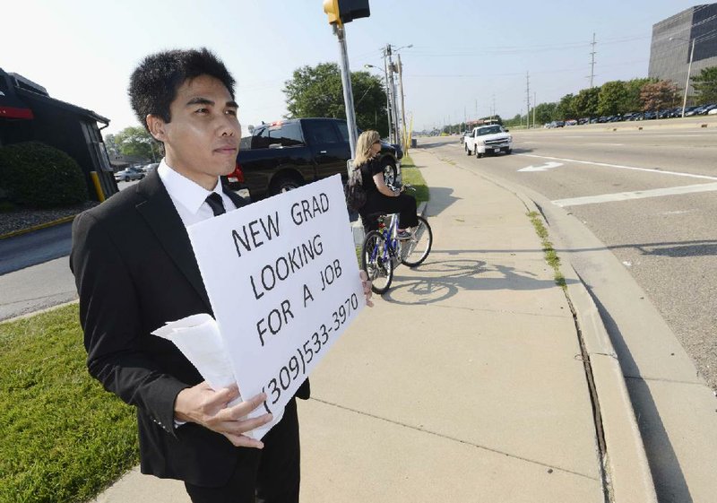 In this July 22, 2014 photo, Danu Phromrat, a recent Illinois State University economics graduate, stands on a busy intersection holding a sign looking for a job in Bloomington, Ill. Phromrat, 27, of Thailand, was also handing out resumes to motorists who showed interest. Phromrat spent four days trying and was hired Tuesday, July 29 by a commercial and residential construction company in Bloomington as a full-time accounting assistant. (AP Photo/The Pantagraph, Steve Smedley)
