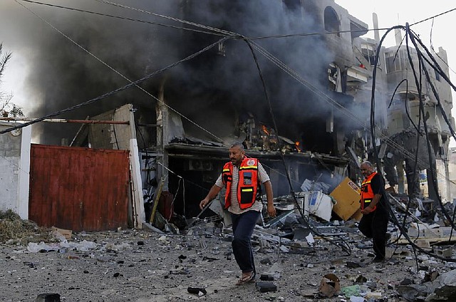 Palestinian firefighters work around the burning rubble of a milk factory in Gaza City that was hit Thursday by an Israeli airstrike.