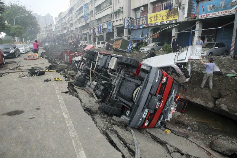 People inspect vehicles tipped over following multiple explosions from an underground gas leak in Kaohsiung, Taiwan, early Friday, Aug. 1, 2014. A massive gas leakage early Friday caused five explosions that killed scores of people and injured over 200 in the southern Taiwan port city of Kaohsiung. (AP Photo) TAIWAN OUT