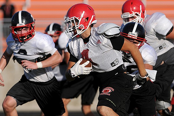 Farmington running back Justice Hobbs caries the ball during 7-on-7 scrimmages at a team camp hosted by Gravette in Lions Stadium on Monday, July 28, 2014.