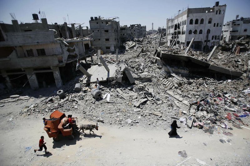 Palestinians, with the help of a donkey cart, carry their belongings through the heavily bombed Gaza City neighborhood of Shijaiyah, close to the Israeli border, on Friday, Aug. 1, 2014. 