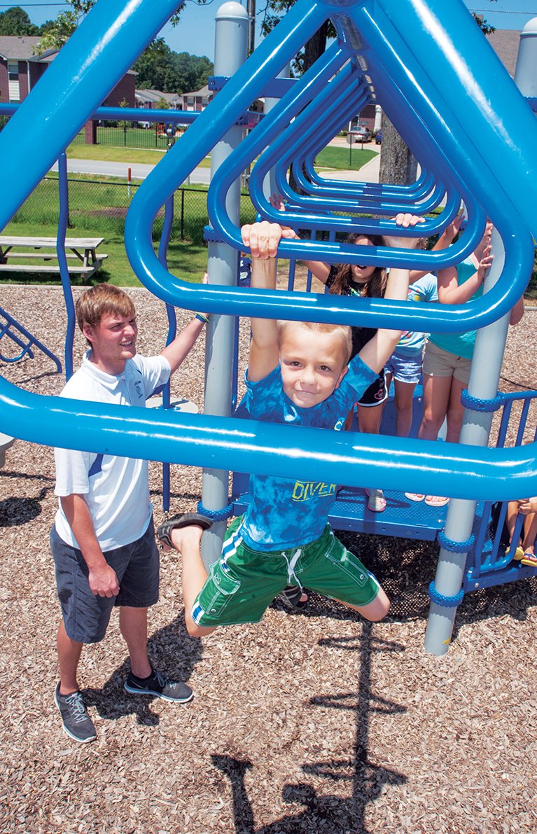 Chad Knight, left, the program director for the Boys and Girls Club of Bryant, watches as Chaney Crosby, 6, swings from one bar to the next on some of the playground equipment at the facility. The club marked its 10-year anniversary of service to the community in July.
