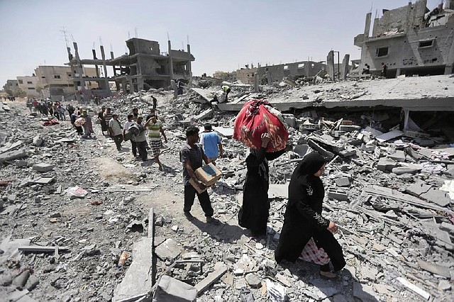 Palestinians carry their belongings after salvaging them from their destroyed houses in the heavily bombed town of Beit Hanoun, Gaza Strip, close to the Israeli border, Friday, Aug. 1, 2014. A three-day Gaza cease-fire that began Friday quickly unraveled, with Israel and Hamas accusing each other of violating the truce. (AP Photo/Lefteris Pitarakis)