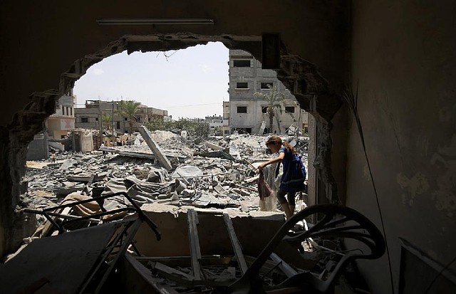 A Palestinian girl salvages belongings Saturday in Gaza City after her family’s house was destroyed in an overnight Israeli airstrike.