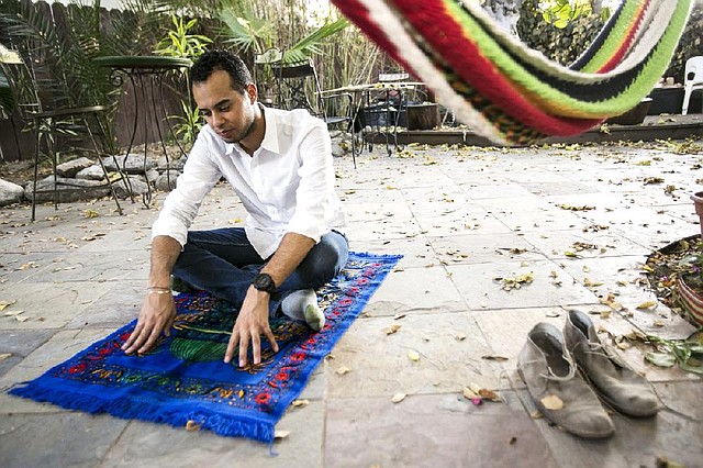 American Muslim Omar Akersim, 26, poses for a photo on his prayer rug  at his home in Los Angeles Friday, Aug. 1, 2014. Nearly 40 percent of the estimated 2.75 million Muslims in the U.S. are American-born and the number is growing, with the Muslim population skewing younger than the U.S. population at large, according to a 2011 survey by the Pew Research Center. (AP Photo/Damian Dovarganes)