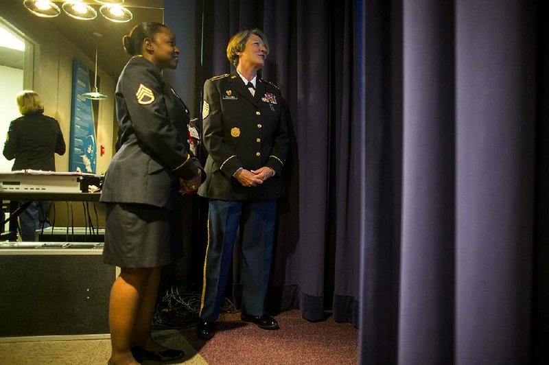 Arkansas National Guard Staff Sgt. Stephanie Eddington (left) and Command Sgt. Maj. Deborah Collins watch a slide from backstage before Collins’ retirement ceremony Saturday at Camp Robinson in North Little Rock.