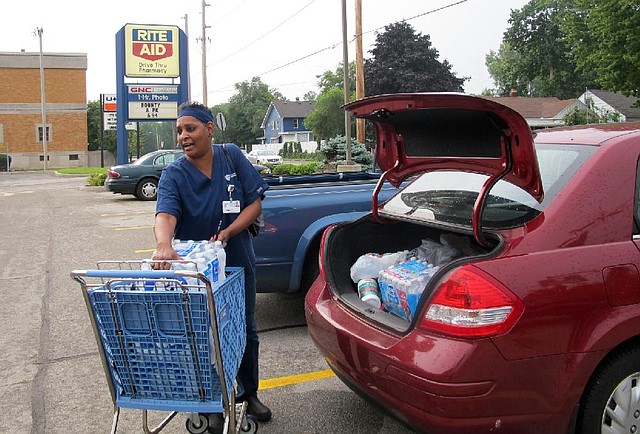 Sharon Green loads bottled water into her car she bought after Toledo warned residents not to use its water, Saturday, Aug. 2, 2014 in Toledo, Ohio.   About 400,000 people in and around Ohio's fourth-largest city were warned not to drink or use its water after tests revealed the presence of a toxin possibly from algae on Lake Erie. (AP Photo John Seewer)