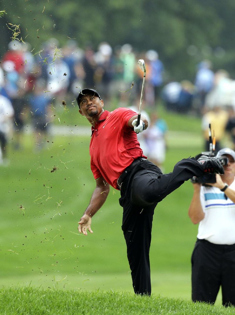 Tiger Woods makes an awkward follow through after hitting from the lip of a fairway bunker on the second hole during the final round of the Bridgestone Invitational golf tournament Sunday, Aug. 3, 2014, at Firestone Country Club in Akron, Ohio. (AP Photo/Mark Duncan)