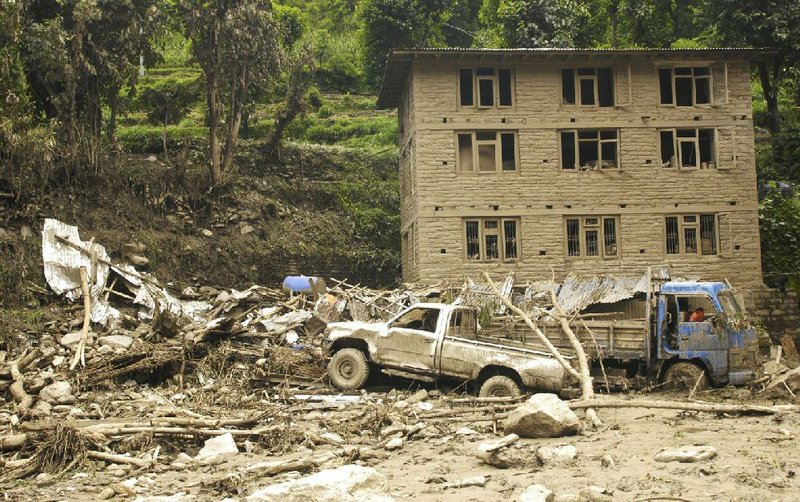 Damaged vehicles lie among the debris after a massive landslide in village Mankha, about 120 kilometers (75 miles) east of Katmandu, Nepal, Sunday, Aug.3, 2014. Nepalese officials say there is no chance of finding any of the more than 150 people, who are believed to have been buried by the early Saturday landslide in northern Nepal. (AP Photo/Arpan Shrestha)