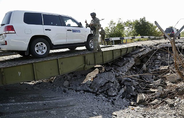 A convoy of international forensic experts and members of the OSCE mission in Ukraine travel across a damaged bridge, near Debaltsevo village, eastern Ukraine Sunday, Aug. 3, 2014, as they travel to of the Malaysia Airlines Flight 17 plane crash site. (AP Photo/Dmitry Lovetsky)