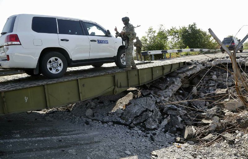 A convoy of international forensic experts and members of the OSCE mission in Ukraine travel across a damaged bridge, near Debaltsevo village, eastern Ukraine Sunday, Aug. 3, 2014, as they travel to of the Malaysia Airlines Flight 17 plane crash site. (AP Photo/Dmitry Lovetsky)