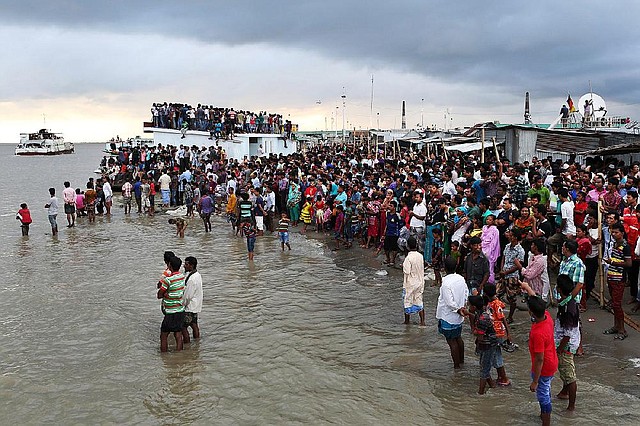 People gather on the banks of  the River Padma after a passenger ferry capsized in Munshiganj district, Bangladesh, Monday, Aug. 4, 2014. A passenger ferry carrying hundreds of people capsized Monday in central Bangladesh, and at least 44 people either swam to safety or were rescued but the number of missing passengers is not yet known. (AP Photo/ A.M. Ahad)