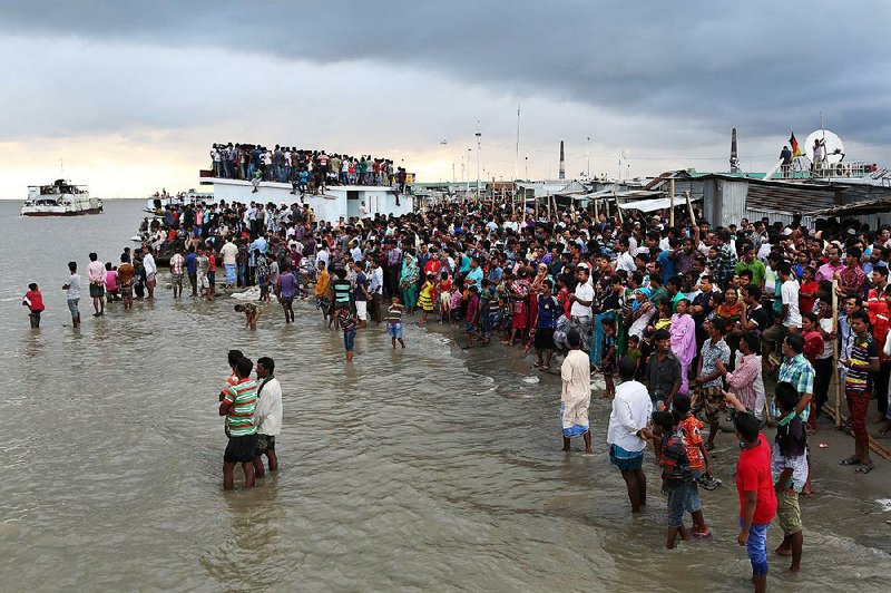 People gather on the banks of  the River Padma after a passenger ferry capsized in Munshiganj district, Bangladesh, Monday, Aug. 4, 2014. A passenger ferry carrying hundreds of people capsized Monday in central Bangladesh, and at least 44 people either swam to safety or were rescued but the number of missing passengers is not yet known. (AP Photo/ A.M. Ahad)