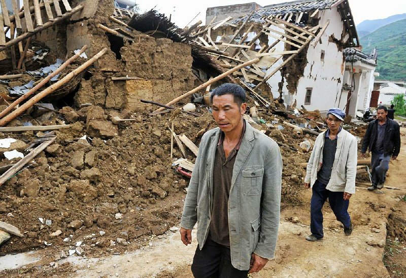 People walk by collapsed houses after Sunday's earthquake in Ludian County of Zhaotong City in southwest China's Yunnan Province, Monday, Aug. 4, 2014. Rescuers dug through shattered homes Monday looking for survivors. (AP Photo/Kyodo News)