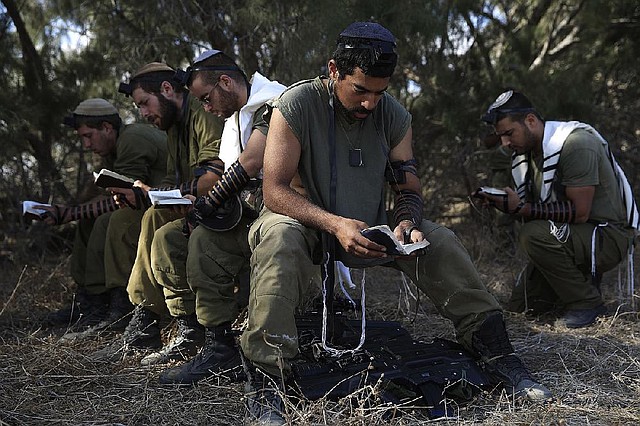 Israeli reserve soldiers pray after returning to Israel from the Gaza Strip near the Israel Gaza border, Monday, Aug. 4, 2014. A brief cease-fire declared by Israel and troop withdrawals slowed violence in the Gaza war Monday, but an attack on an Israeli bus that killed one person in Jerusalem underscored the tensions still simmering in the region as Israeli airstrikes resumed late in the day. (AP Photo/Tsafrir Abayov)