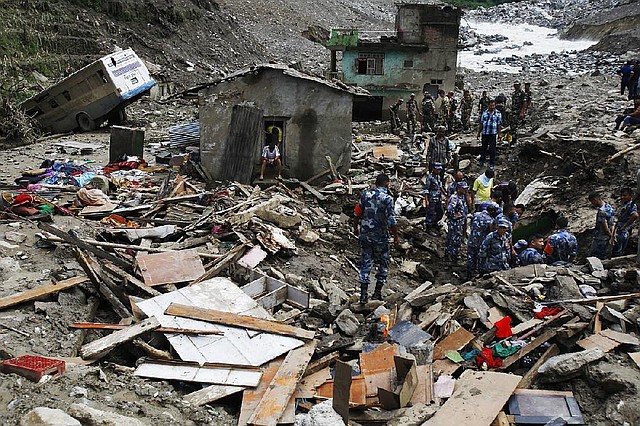 Nepalese rescuers search for bodies of victims of Saturday's landslide as a damaged school bus lies on left, in Mankha, about 120 kilometers (75 miles) east of Katmandu, Nepal, Monday, Aug.4, 2014. Nepalese authorities said there is no hope that more than 150 missing people are still alive after being buried by piles of rocks, mud and upturned trees.  (AP Photo/Niranjan Shrestha)