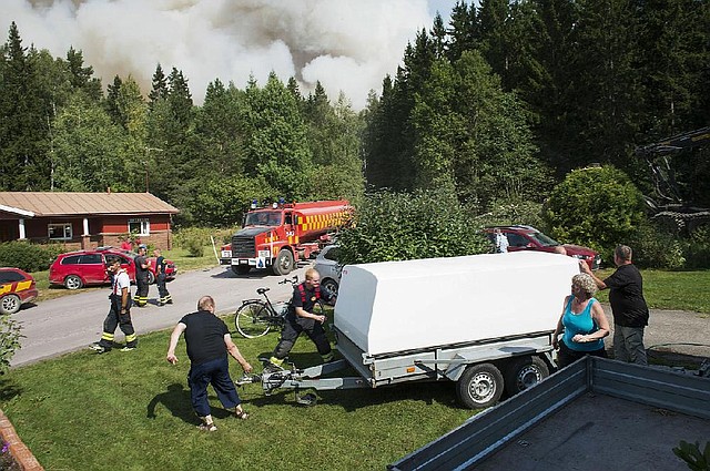 Home owners and emergency personnel prepare to evacuate a village threatened by the approaching forest fire near Sala, Central Sweden, on Monday Aug. 4, 2014. The fire has swept over a wide swathe of land for nearly a week, and firefighters predict it will burn for weeks to come. It is classified as the worst forest fire in Sweden's modern history.  (AP Photo / Fredrik Sandberg)  SWEDEN OUT