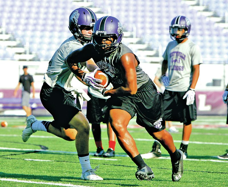 Staff Photo DAVID GOTTSCHALK Javontae Smith, Fayetteville High School running back, takes a handoff from quarterback Taylor Powell during practice Monday at Harmon Field in Fayetteville.
