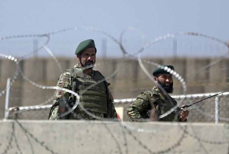 Afghanistan National Army soldiers stand guard at a gate of Camp Qargha, west of Kabul, Afghanistan, Tuesday, Aug. 5, 2014. A man dressed in an Afghan army uniform opened fire Tuesday on foreign troops at a military base, causing casualties, an Afghan military spokesman said. In a statement NATO said it was investigating an "incident" involving both Afghan and international troops at Camp Qargha which trains officers for the country's army. 