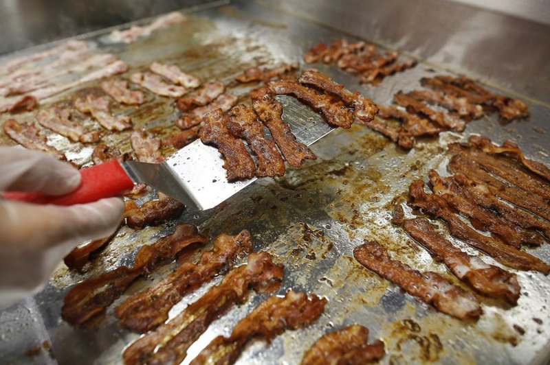 A chef cooks bacon on a griddle at a Five Guys hamburger restaurant in London in this file photo. A decline in the size of the nation’s pig herd has pushed retail bacon prices up 10 percent this year.