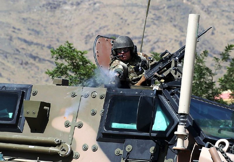 A NATO soldier fires an apparent warning shot toward journalists Tuesday as they gathered near the main gate of Camp Qargha outside Kabul after a shooting on the base earlier in the day.


