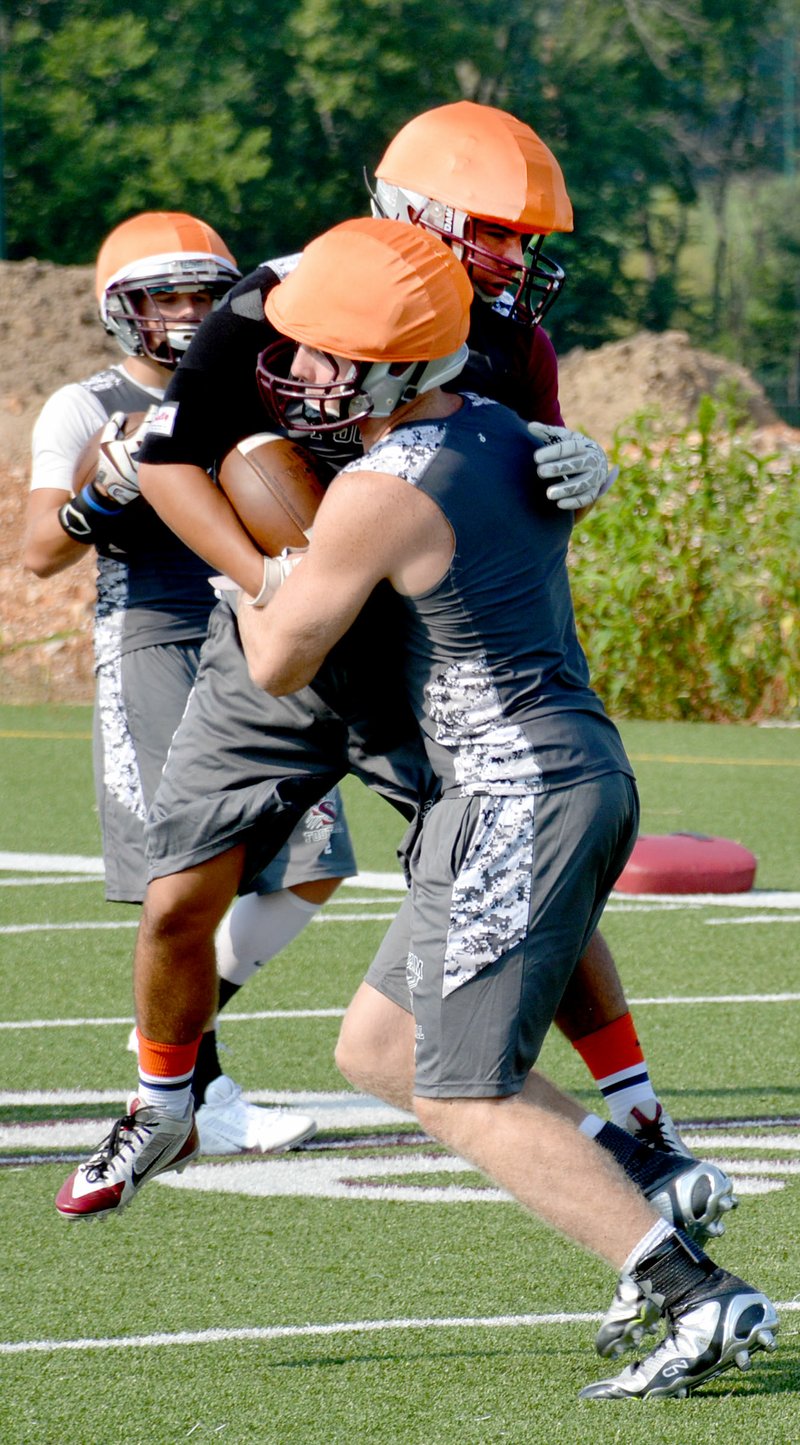 Graham Thomas/Herald-Leader Siloam Springs senior cornerback Tyler Burke, left, is wrapped up by senior Parker Baldwin during football practice Tuesday at Siloam Springs High School.