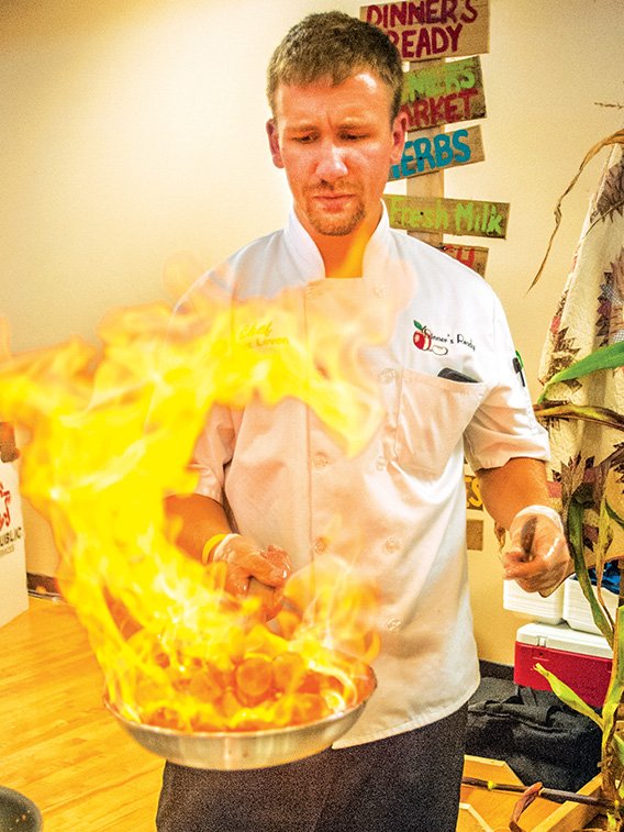 Chef Alex Leven with Dinner’s Ready gets the fire going as he prepares bananas Foster for guests passing through the line during the Taste of Bryant on July 31.