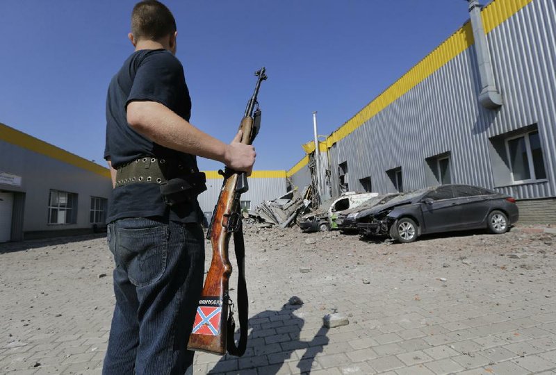 A pro-Russia fighter stands near a damaged building Wednesday in Donetsk, eastern Ukraine, after a night artillery attack that reportedly killed three civilians. 