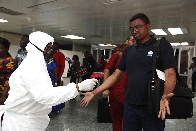 A Nigerian port health official takes a temperature reading Wednesday of an arriving passenger at the airport in Lagos as part of stepped-up measures to check the spread of the Ebola virus. 