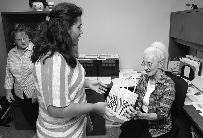 STAFF PHOTO SAMANTHA BAKER @NWASAMANTHA Maria Namio, 16, center, gives Rita Curtis a Marshallese handicraft as a &#8220;thank you&#8221; for her help Tuesday at the Springdale Public Schools Administration Building. Namio was part of a group of Marshallese students on a walking tour of downtown Springdale. The group stopped at the high school, administration office, Shiloh Museum and the city administration offices.