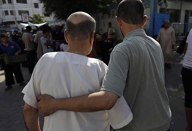 A Palestinian helps an elderly man as they walk into a clinic in Gaza City, northern Gaza Strip, Wednesday, Aug. 6, 2014. A cease-fire between Israel and Hamas that ended a month of fighting is holding for a second day, ahead of negotiations in Cairo on a long-term truce and a broader deal for the war-ravaged Gaza Strip.