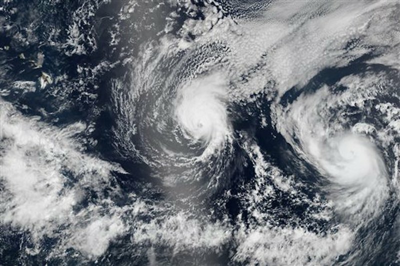 This Aug. 5, 2014, satellite image provided by NASA shows two tropical Pacific Ocean hurricanes — Iselle at center and Julio at right — bearing down on Hawaii, top left. Hurricane Iselle is expected to reach Hawaii Thursday night, Aug. 7, 2014. Tracking close behind it is Hurricane Julio, which strengthened early Thursday into a Category 2 storm. 