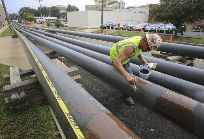 Kyle Jimeson with Michels Corporation of Wisconsin coats pipes with a sealant Thursday while working on a new gas pipeline that will replace the gas pipelines on the Broadway Bridge.