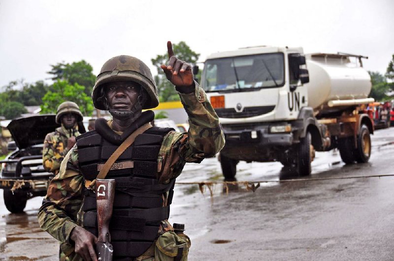 A Liberian soldiers stops people at a security checkpoint setup to lamp down on people traveling due to the Ebola virus, on the outskirts of Monrovia, Liberia, Thursday, Aug. 7, 2014. Soldiers clamped down on people trying to travel to Liberia's capital Thursday from rural areas hard-hit by the Ebola virus hours after the president declared a national state of emergency. (AP Photo/Abbas Dulleh)