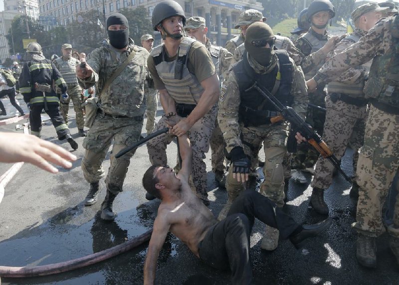 Special forces police battalion officers detain an activist during a clash in Independence Square in Kiev, Ukraine, on Thursday, Aug. 7, 2014.  The unrest had started earlier Thursday, after the Kiev authorities attempt to dismantle some of the barricades. Activists confronted city workers attempting to clear a central square, lighting tires on fire in protest against the city government's move. 