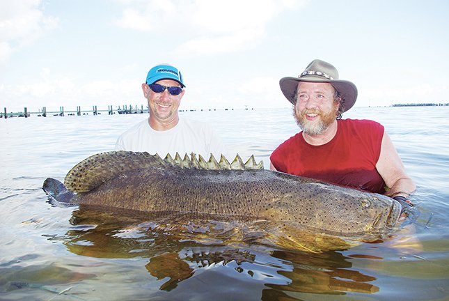 Fishing guide Ryan Rowan, left, helps Keith Sutton lift a 450-pound goliath grouper for a photograph. It’s the biggest fish Sutton has 
ever caught.