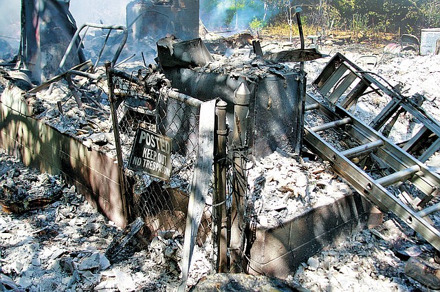 Staff Photo Dan Holtmeyer The charred remains of a rural home smolder after it was destroyed by a fire Thursday. A body was found in the home&#8217;s debris.