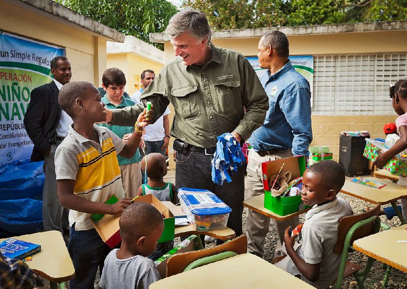 Franklin Graham, the founder of Samaritan’s Purse, hands out shoe boxes to children as part of the organization’s Operation Christmas Child outreach.